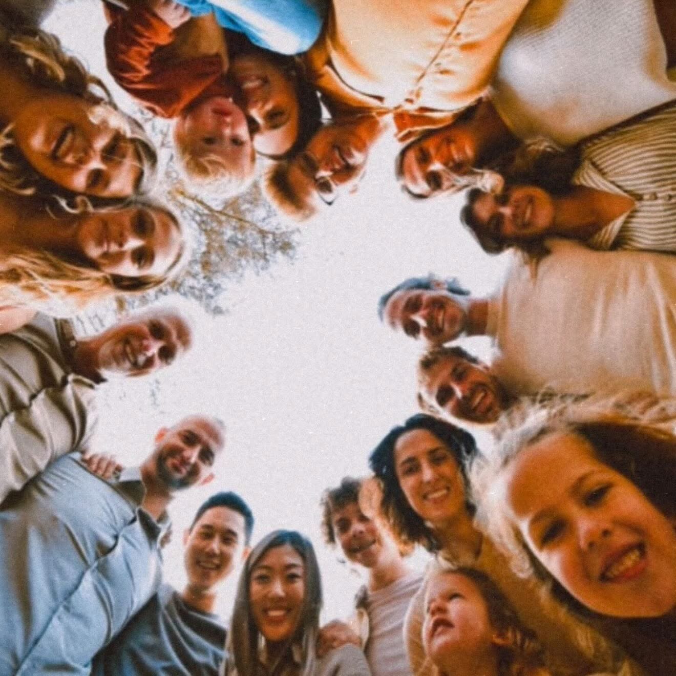 A big family circle looking down at the camera against a bright sky